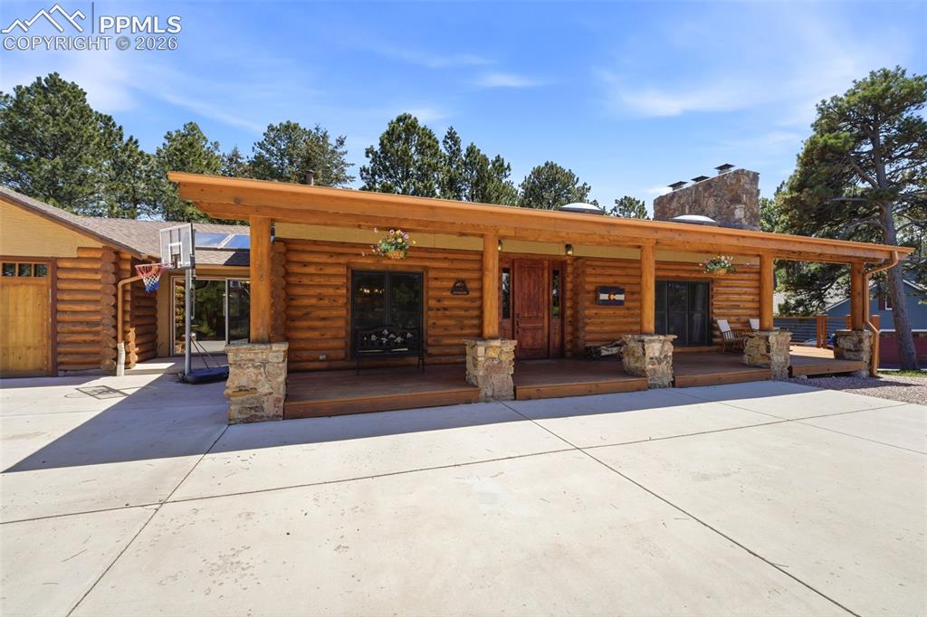Image 3 of 49: Log home exterior featuring a spacious covered porch with stone pillars, a
