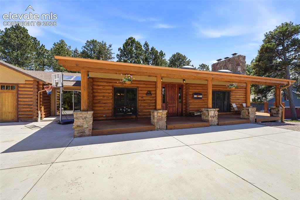 Image 3 of 49: Log home exterior featuring a spacious covered porch with stone pillars, a