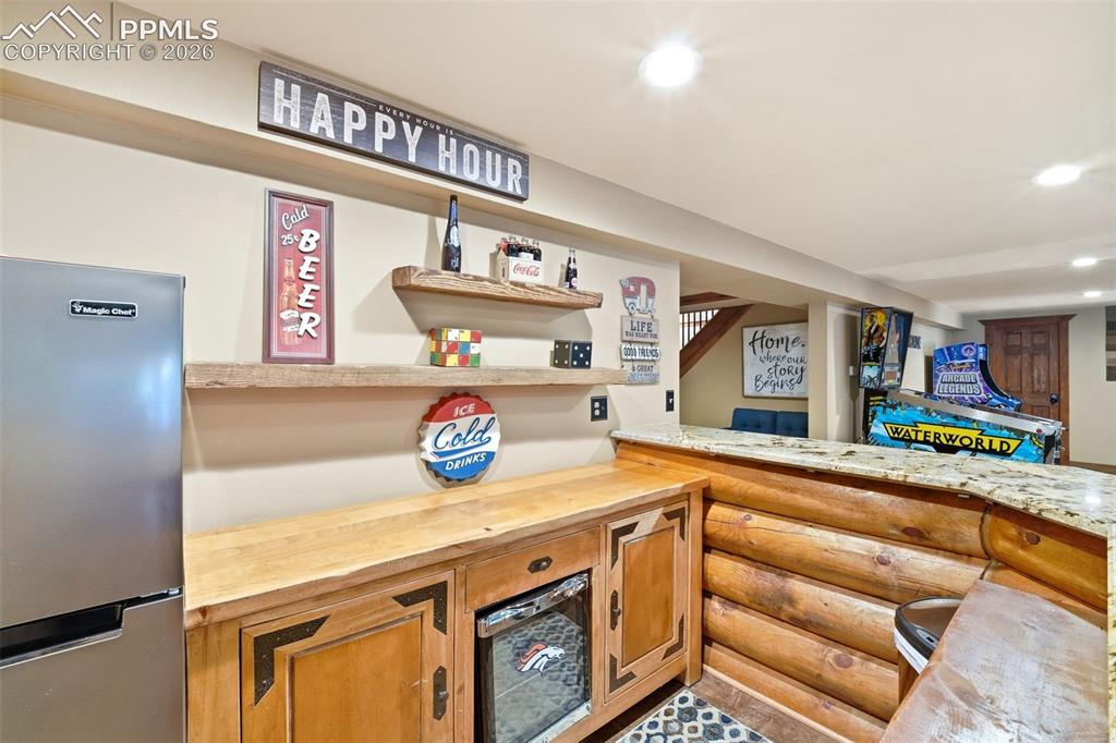 Image 31 of 50: Rustic bar area featuring a granite countertop, log-style bar front, wood-f