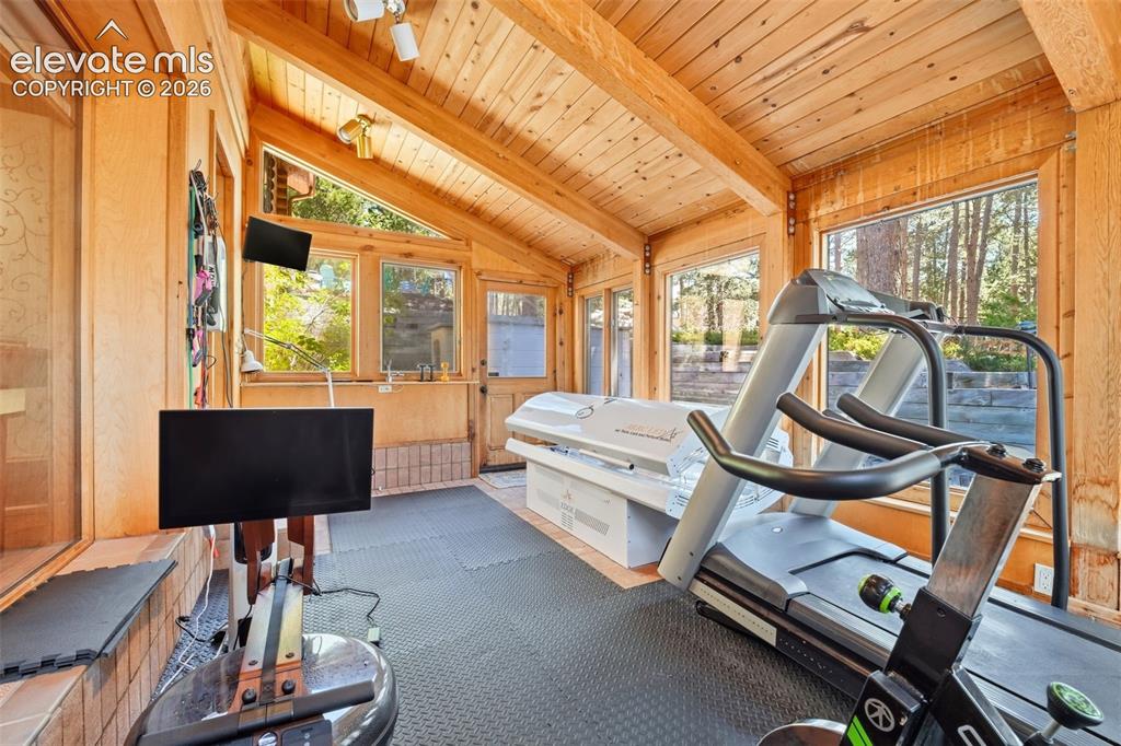 Image 31 of 49: Sunroom with vaulted wood-paneled ceilings, exposed wood beams, and extensi