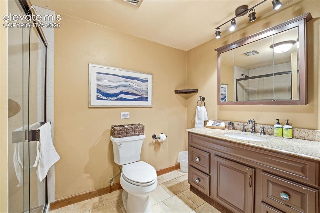 Image 33 of 49: Bathroom featuring a brown wood-finish vanity with an undermount sink and a