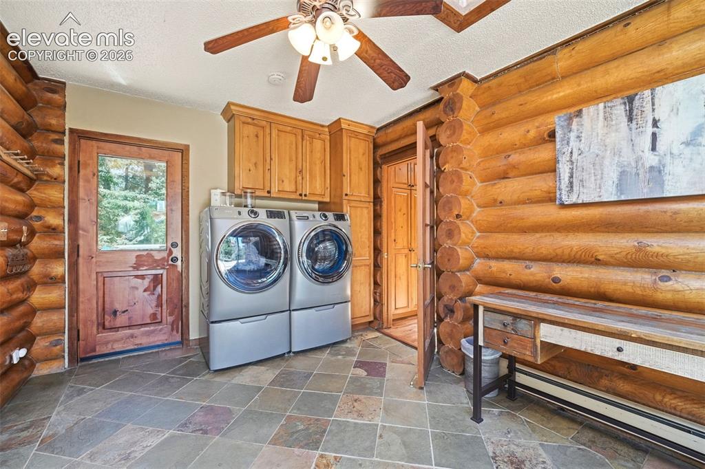 Image 34 of 49: Laundry area featuring log walls, multi-tone slate tile flooring, and a woo