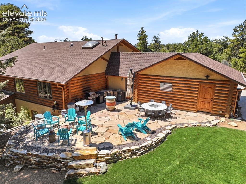 Image 36 of 49: Expansive flagstone patio with a stone retaining wall, featuring a built-in