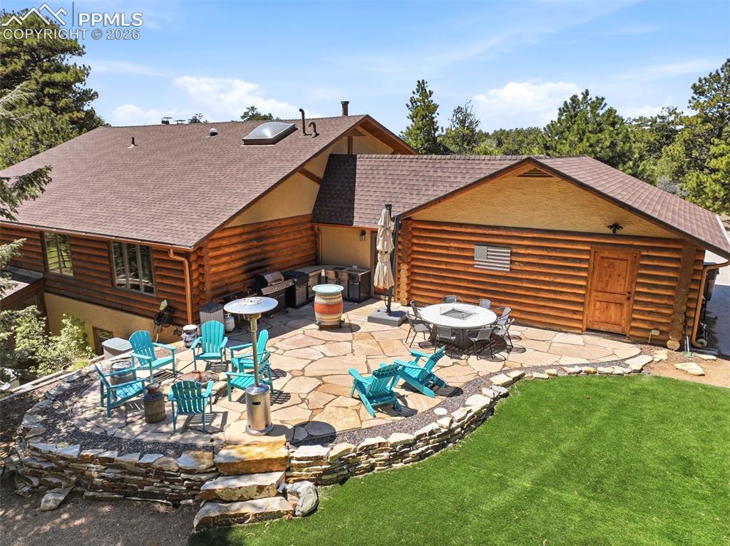 Image 38 of 50: Expansive flagstone patio with a stone retaining wall, featuring a built-in