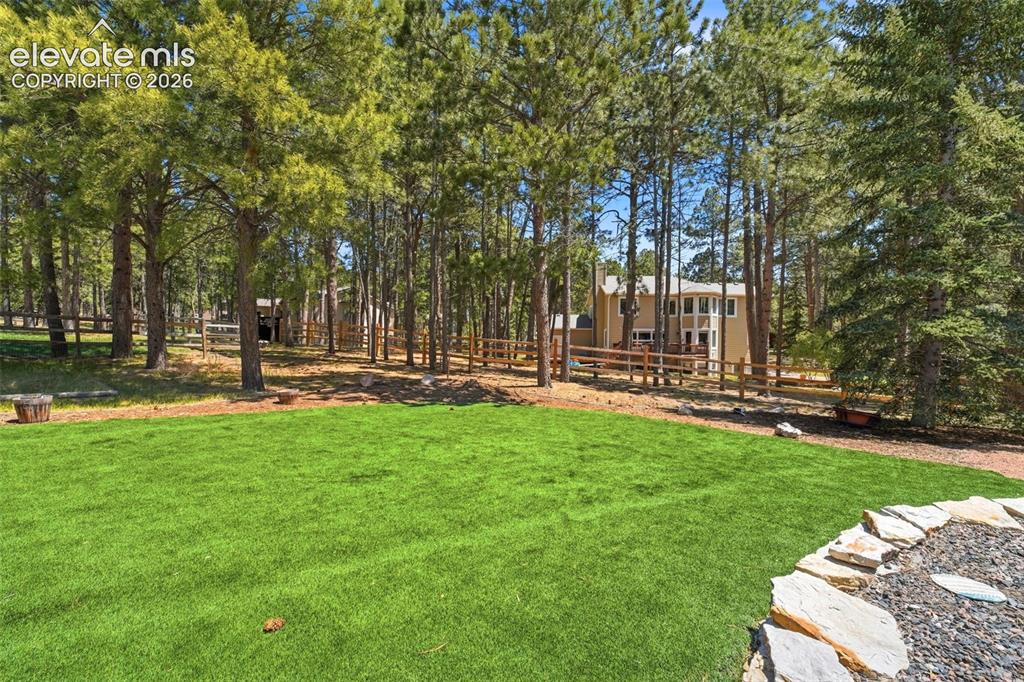 Image 44 of 49: Manicured lawn area with a stone-edged landscape feature