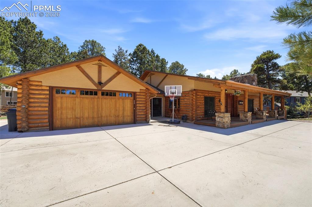 Image 5 of 49: Log-style exterior featuring a spacious concrete driveway, an attached gara