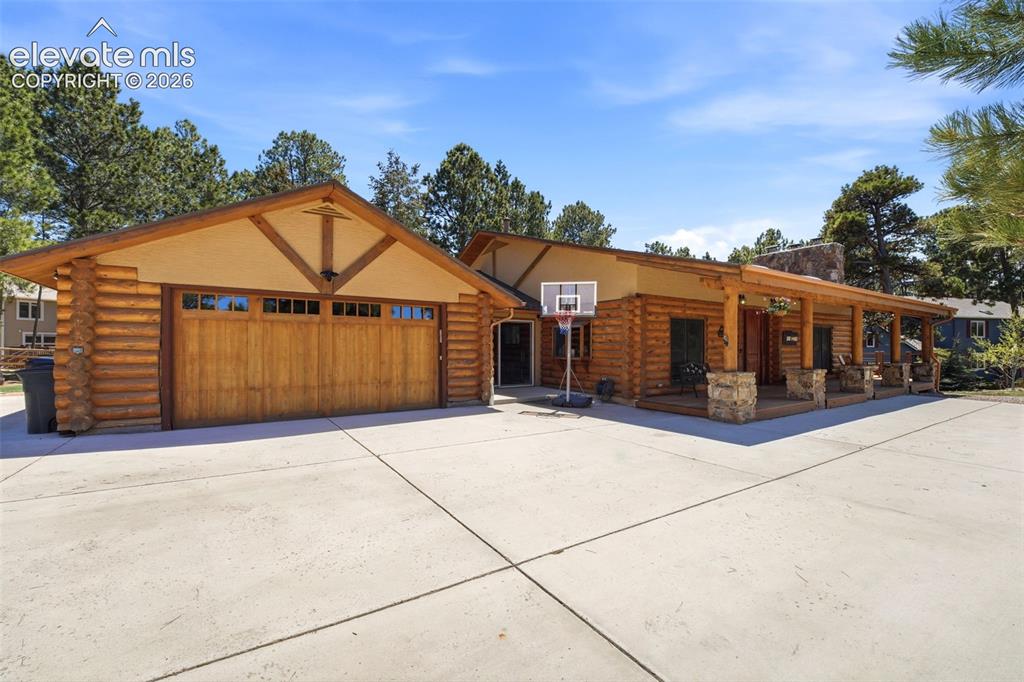 Image 5 of 49: Log-style exterior featuring a spacious concrete driveway, an attached gara
