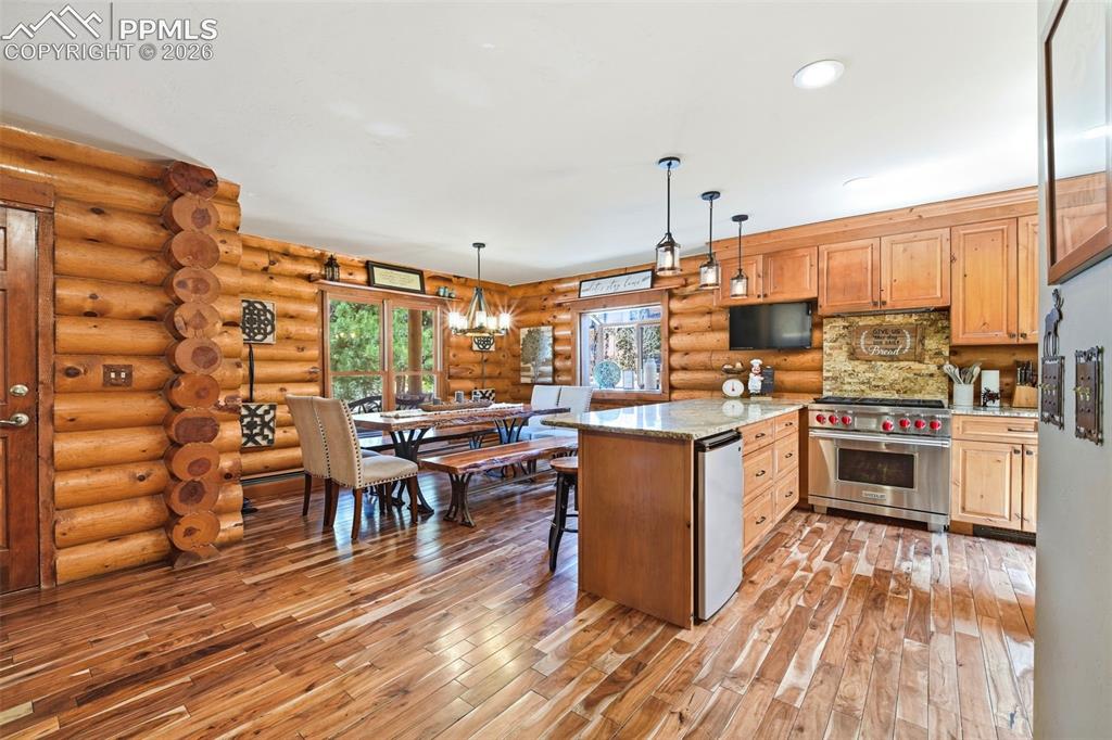 Image 7 of 49: Kitchen with log walls and wood-finish flooring