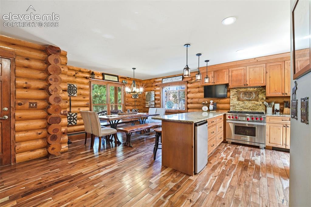 Image 7 of 49: Kitchen with log walls and wood-finish flooring