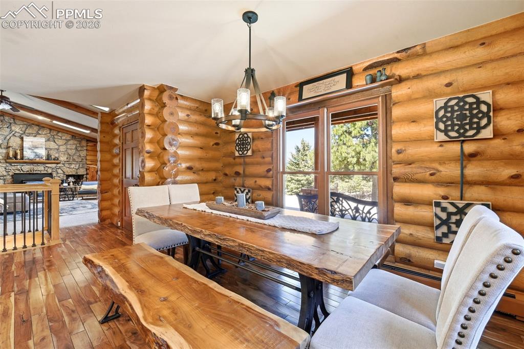 Image 8 of 49: Dining space featuring log walls, wood-finish flooring, and a large window