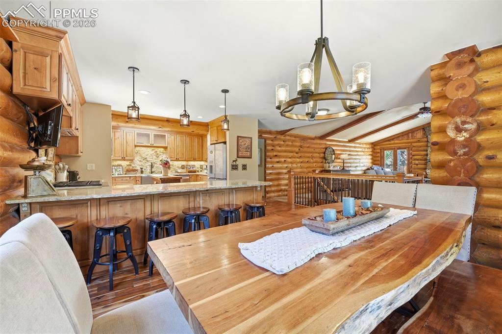 Image 9 of 49: Spacious dining area featuring a live-edge wood table, a chandelier with fr