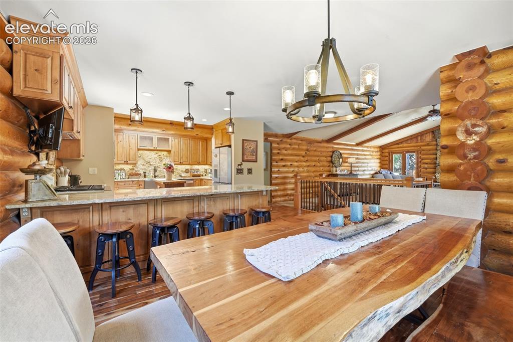 Image 9 of 49: Spacious dining area featuring a live-edge wood table, a chandelier with fr