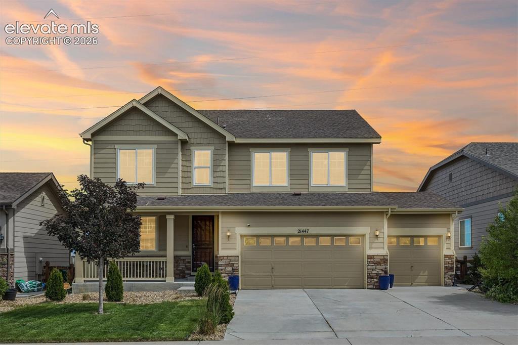 Image 1 of 39: Two-story residence featuring a covered front porch, a three-car garage, an