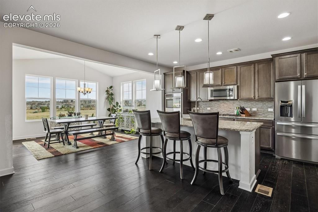 Image 2 of 39: Open-concept kitchen and dining area with dark wood-finish flooring