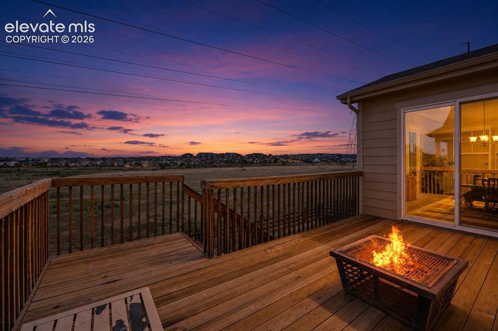 Image 24 of 39: Spacious wood deck with a built-in fire pit, offering outdoor living space