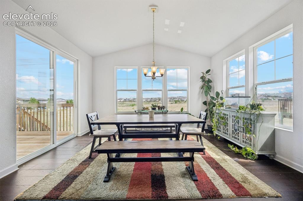 Image 3 of 39: Spacious dining area featuring dark wood-finish flooring, a vaulted ceiling