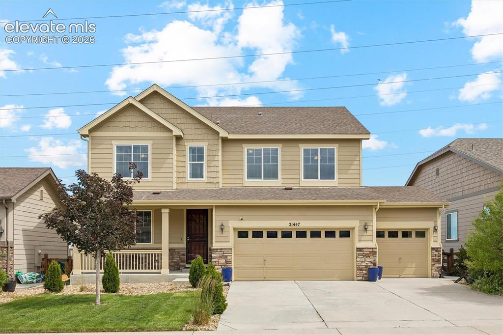 Image 5 of 39: Two-story residence featuring a covered front porch with white railings, a