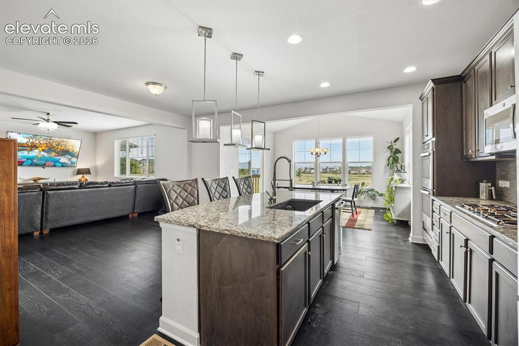Image 7 of 39: Kitchen featuring a large central island with seating, dark wood-finish flo