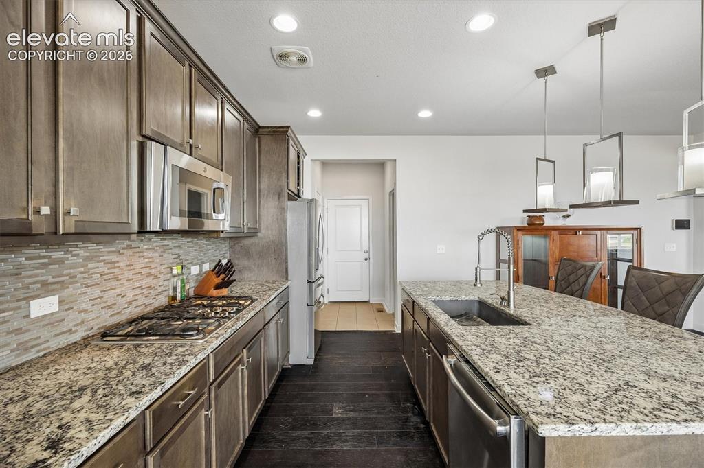 Image 8 of 39: Modern kitchen featuring dark wood-finish flooring, light-colored stone cou
