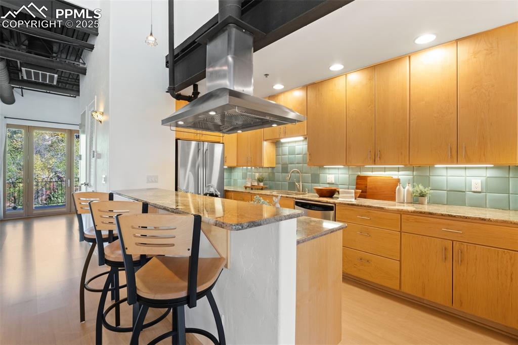 Image 10 of 38: Kitchen with stone counters, stainless steel appliances, an island with a g