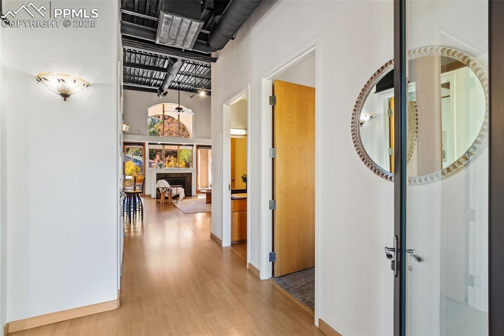 Image 3 of 38: Hallway featuring light wood-style floors and a high ceiling featuring indu