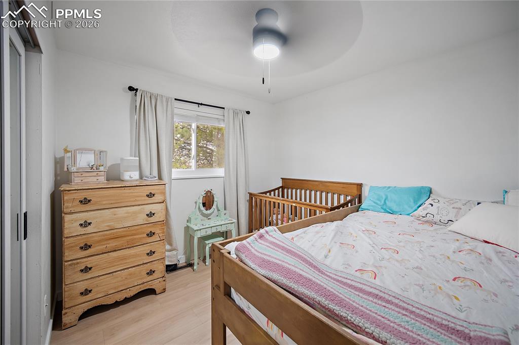 Image 18 of 44: Main level bedroom with laminate flooring and ceiling fan. 