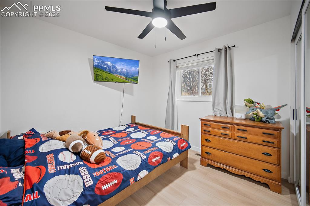 Image 21 of 44: Main level bedroom with laminate flooring and ceiling fan. 