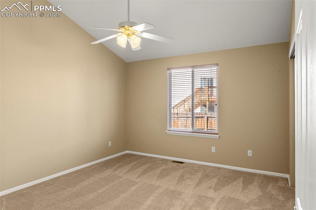 Image 14 of 25: Spare room featuring light colored carpet, lofted ceiling, and ceiling fan