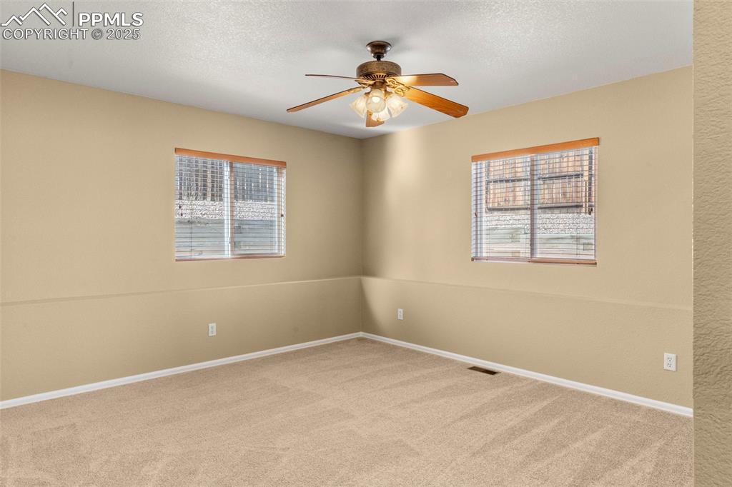 Image 17 of 25: Spare room with light carpet, ceiling fan, and a textured ceiling