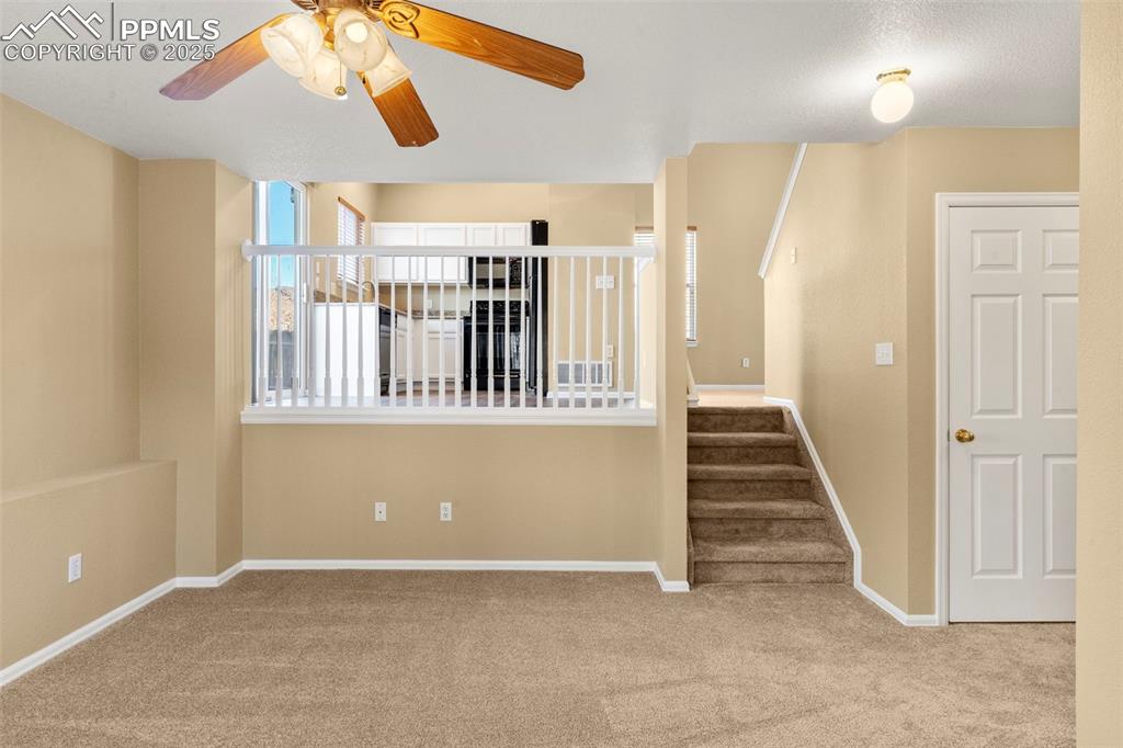 Image 18 of 25: Staircase with carpet floors and a ceiling fan