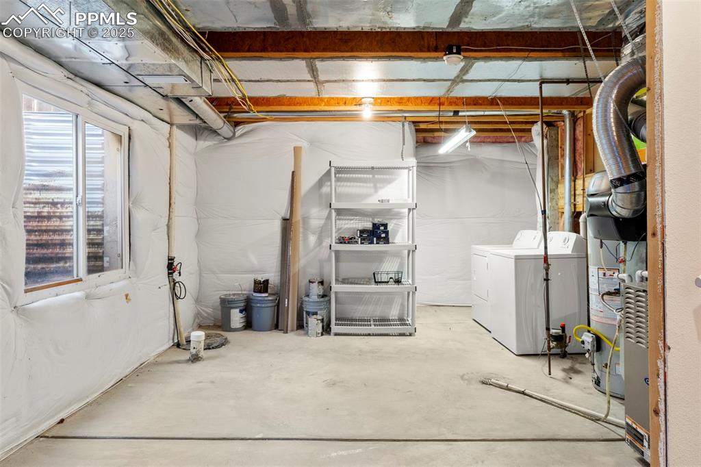 Image 22 of 25: Below grade area with washer and dryer and gas water heater