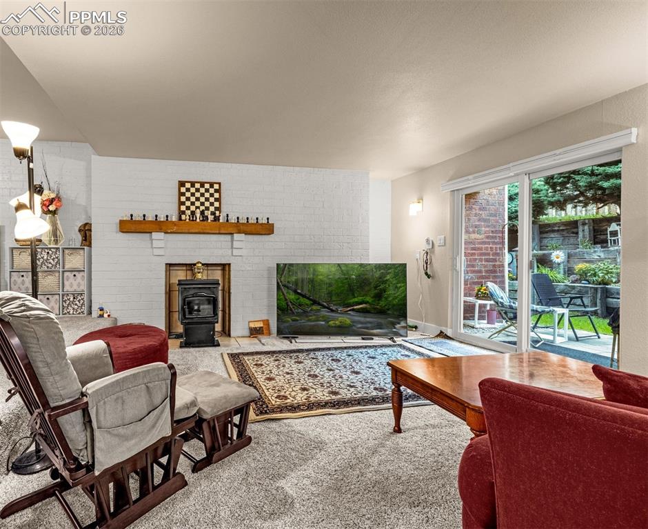 Image 11 of 21: Carpeted living area with a wood stove and brick wall