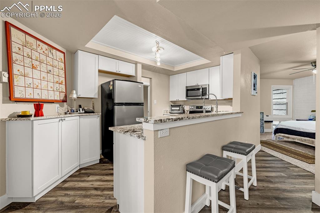 Image 13 of 21: Kitchen with white cabinetry, dark wood finished floors, stainless steel ap