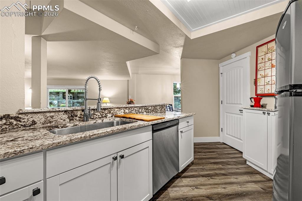 Image 15 of 21: Kitchen featuring light stone counters, white cabinets, dark wood finished 