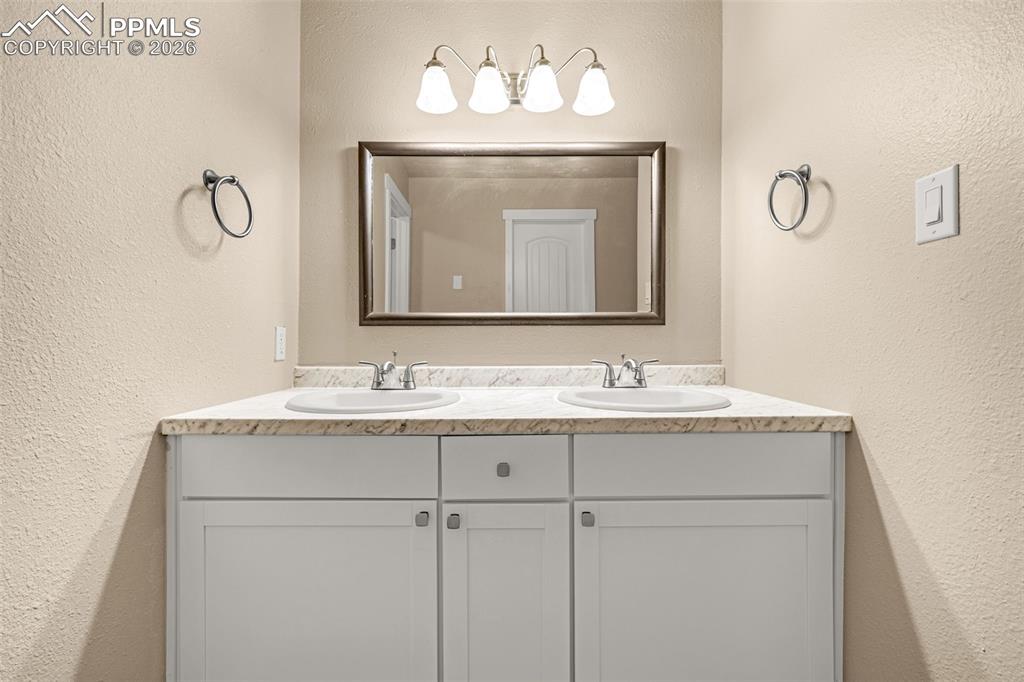 Image 6 of 21: Bathroom with a textured wall and double vanity