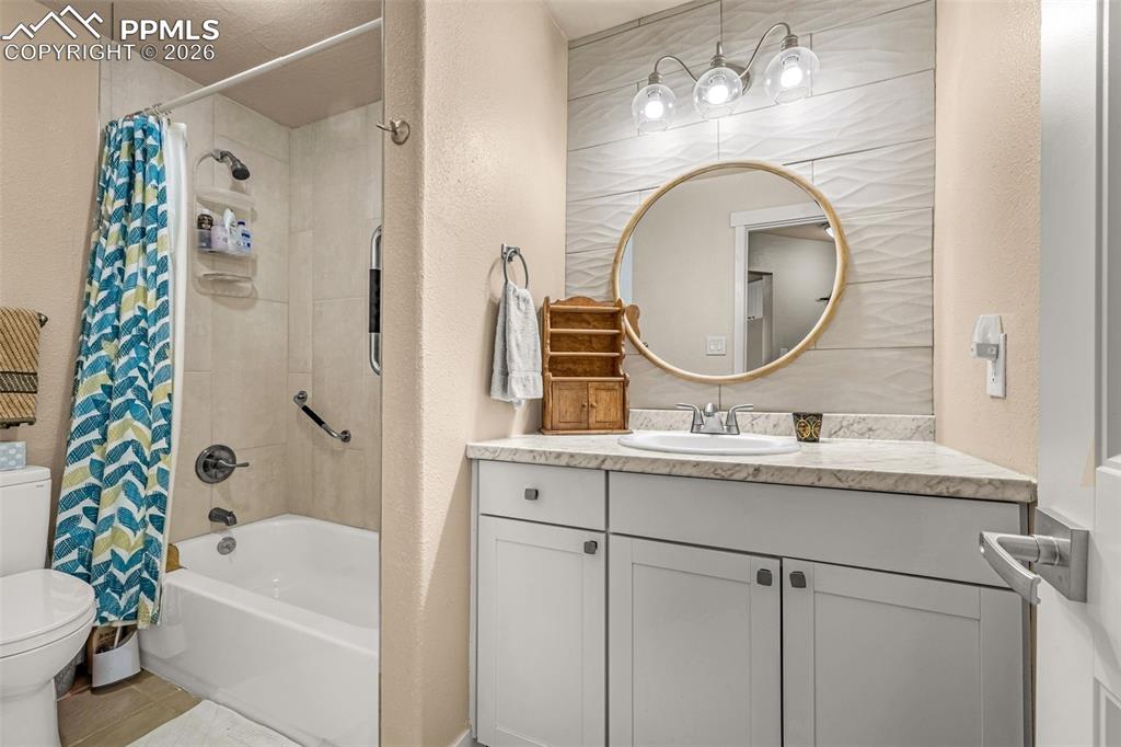 Image 9 of 21: Bathroom with shower / tub combo with curtain, a textured wall, and vanity
