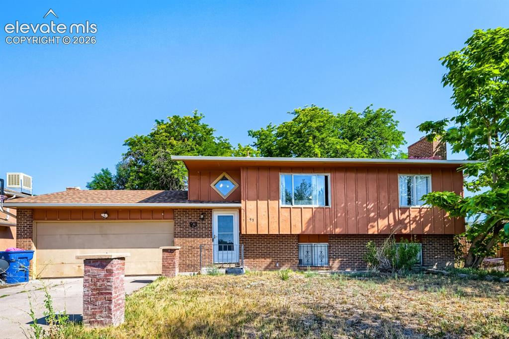 Caption: Split-level residence featuring brick and vertical wood-panel siding