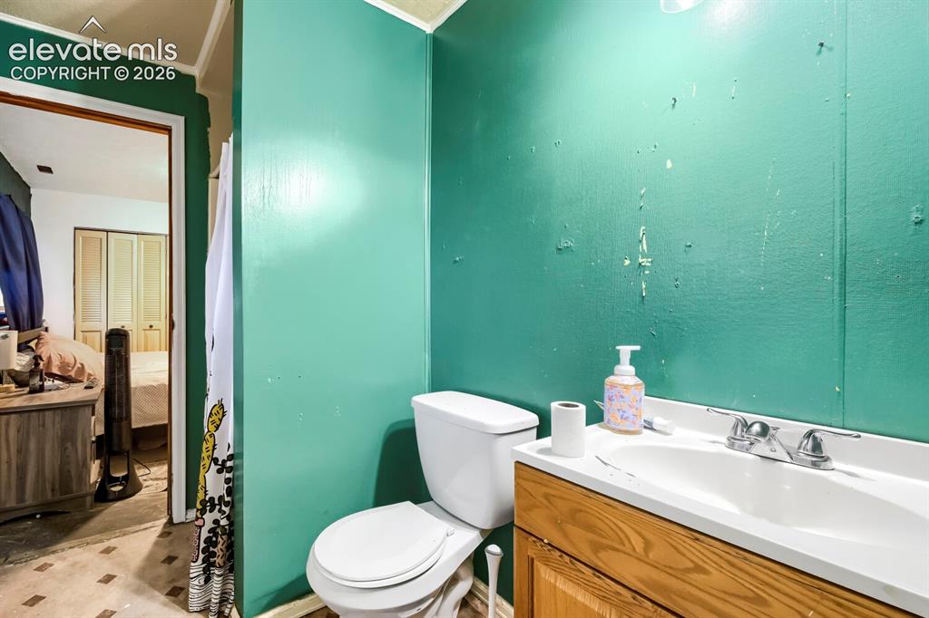 Image 16 of 17: Bathroom featuring a white toilet, wood-finish vanity with an integrated si