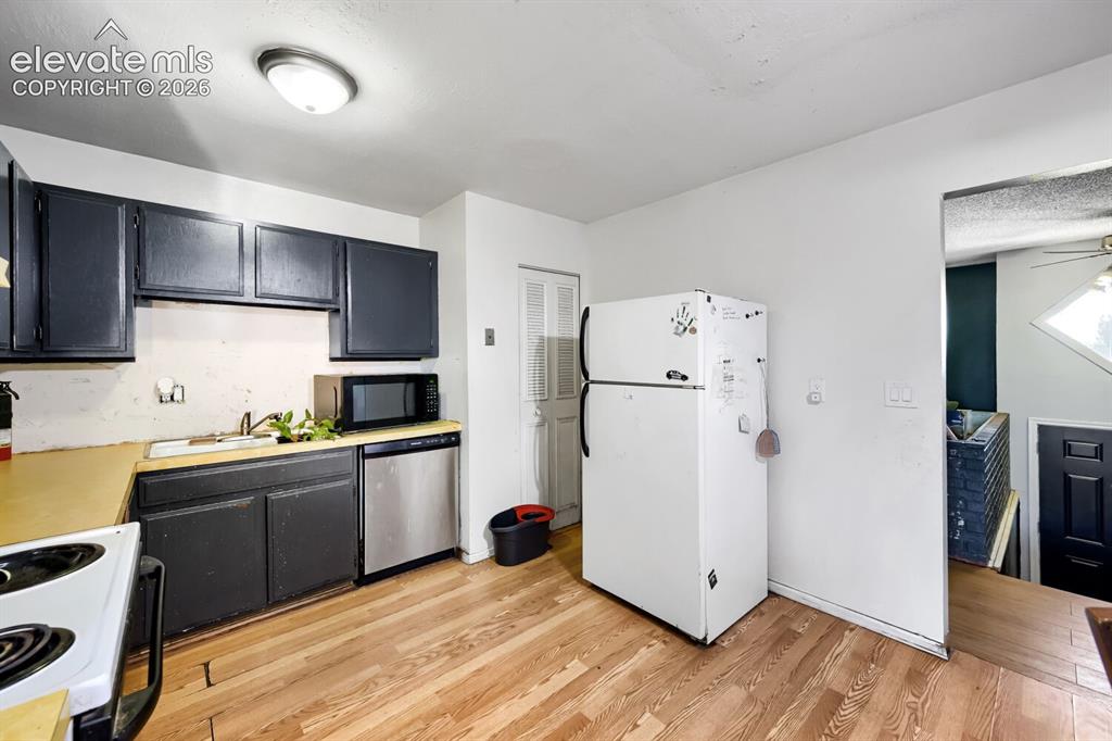 Image 6 of 17: Kitchen featuring wood-finish flooring, dark cabinetry, and a stainless ste
