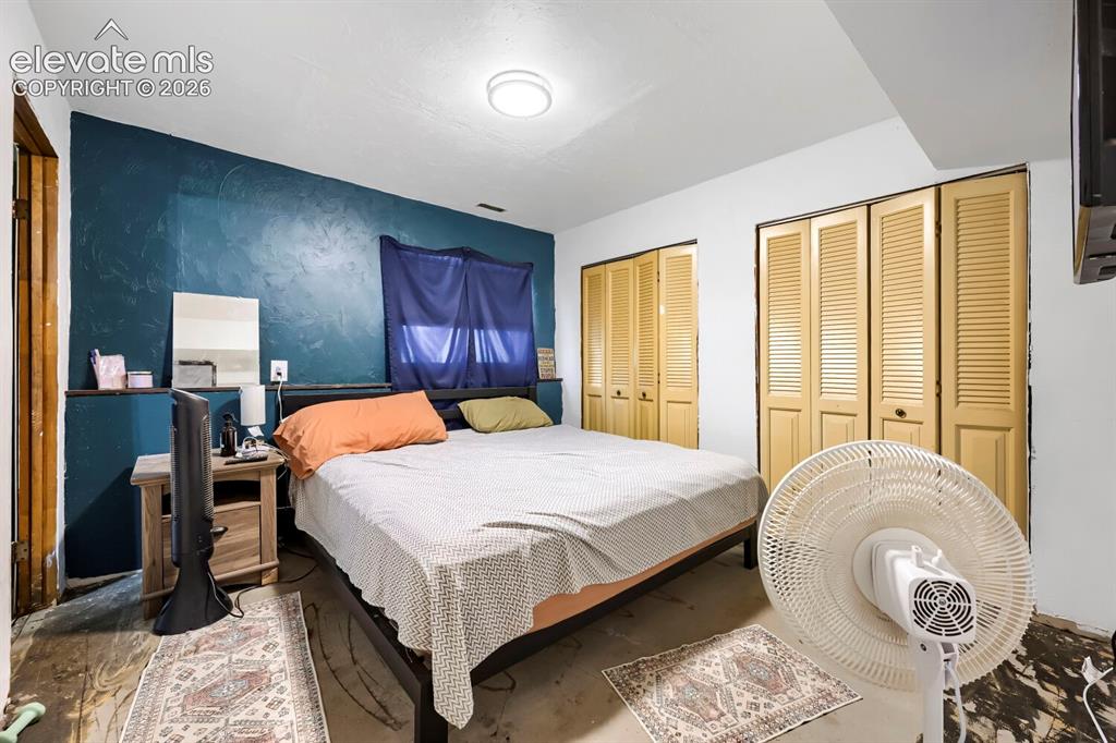 Image 9 of 17: Bedroom featuring a textured accent wall, two sets of louvered bi-fold clos