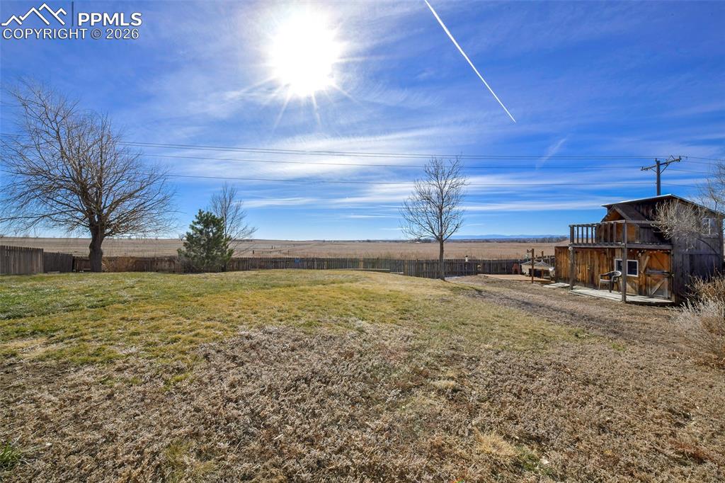 Image 24 of 27: Fenced backyard featuring an outbuilding and a patio