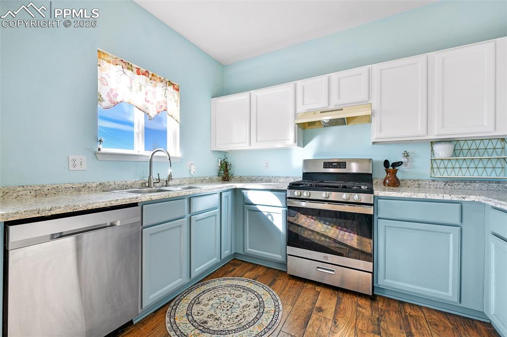 Image 5 of 27: Kitchen featuring stainless steel appliances, under cabinet range hood, dar