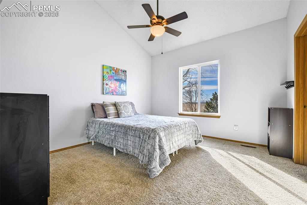 Image 9 of 27: Bedroom featuring carpet flooring, ceiling fan, high vaulted ceiling, and a