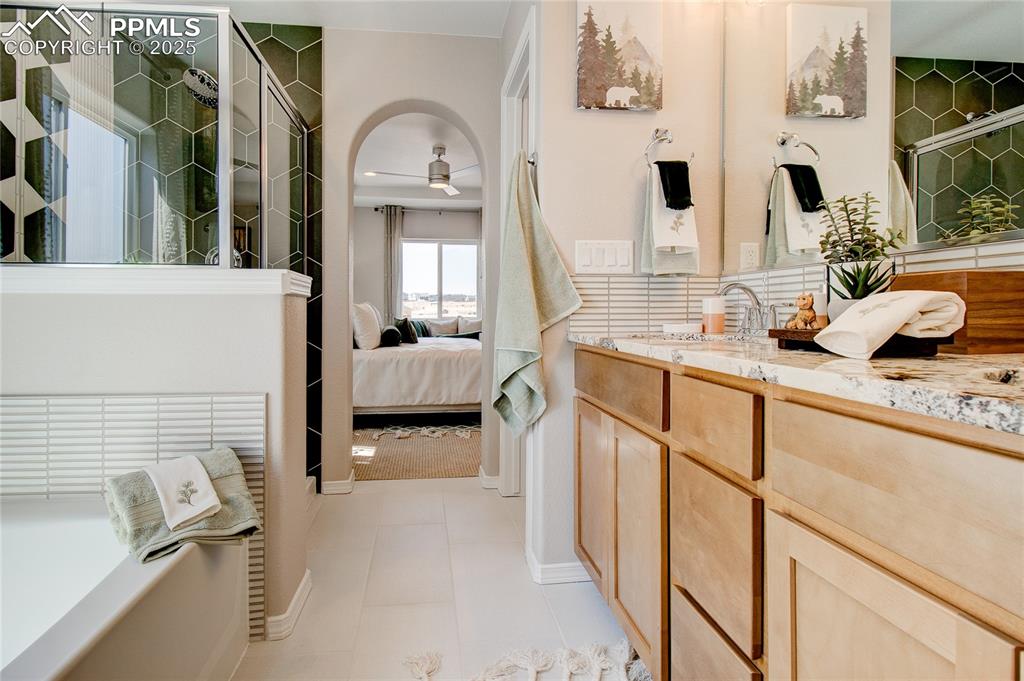 Image 19 of 23: Ensuite bathroom featuring vanity, tiled shower, and a ceiling fan
