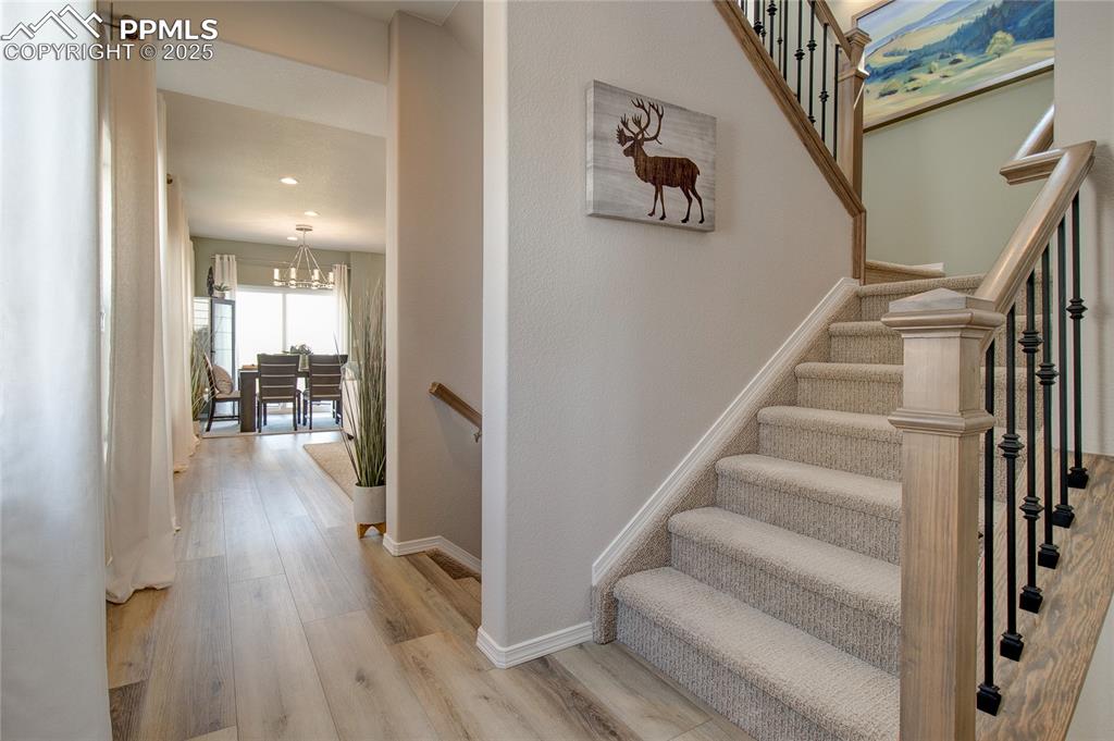 Image 2 of 23: Stairway with wood finished floors, a chandelier, and recessed lighting