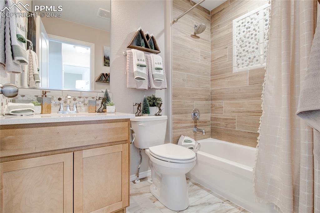 Image 23 of 23: Full bath with shower / bath combo, vanity, and marble finish flooring