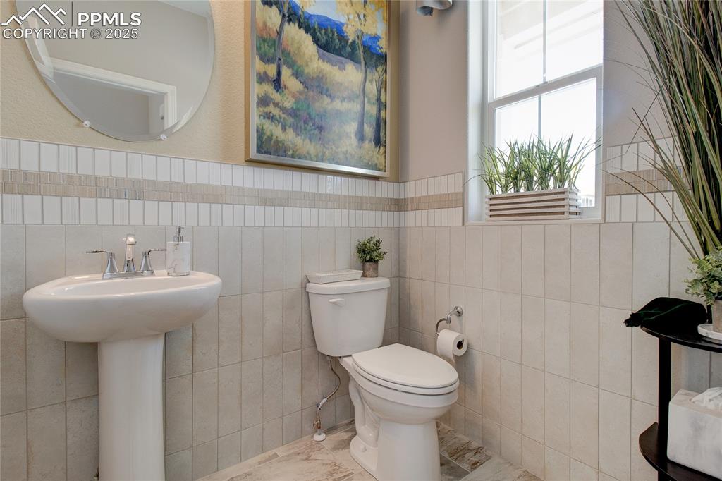 Image 4 of 23: Bathroom featuring tile walls and a wainscoted wall
