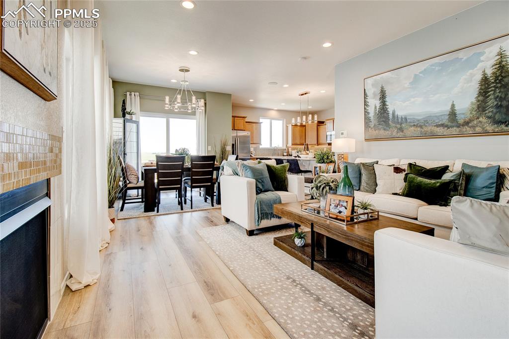 Image 5 of 23: Living area with a chandelier, light wood finished floors, recessed lightin