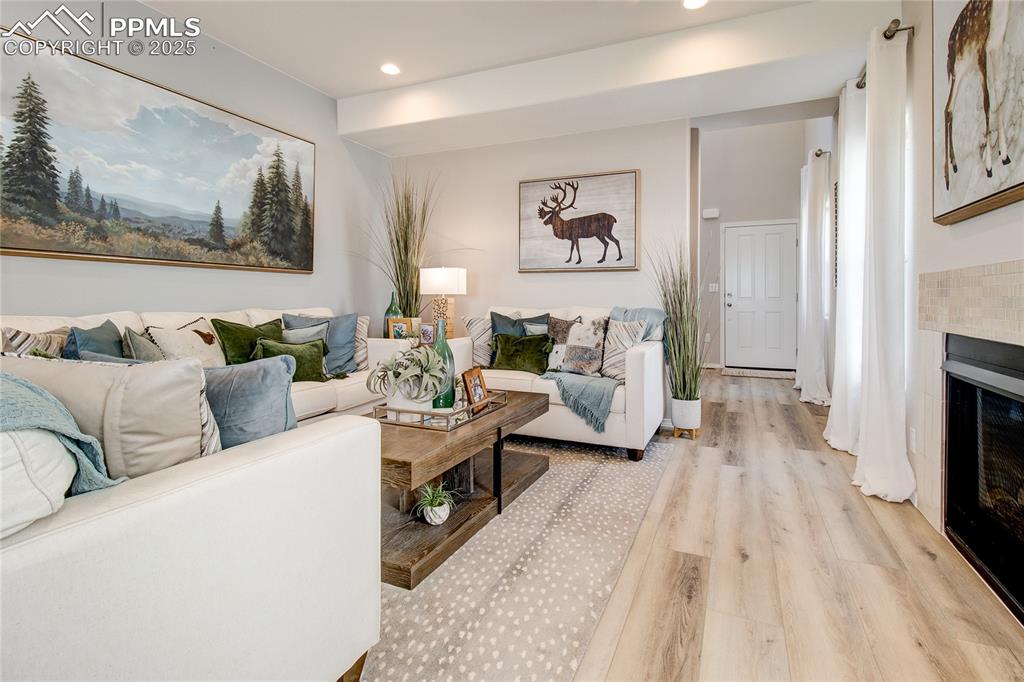 Image 6 of 23: Living area with light wood-style floors, a fireplace, and recessed lightin