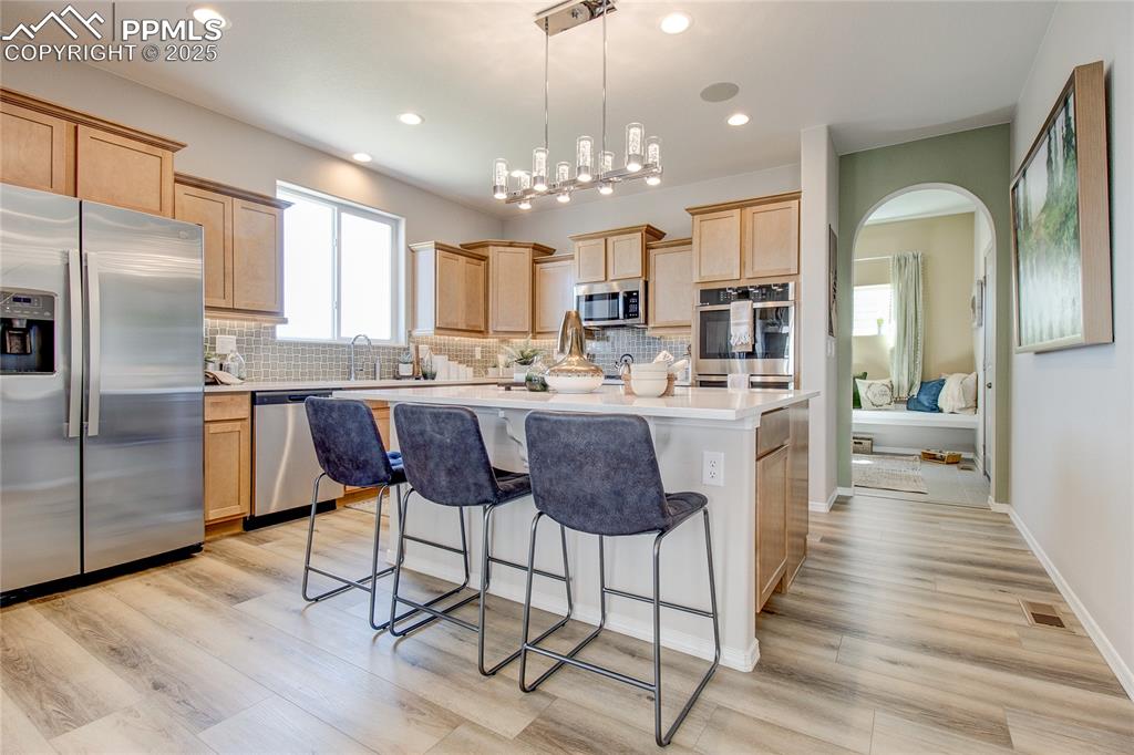 Image 8 of 23: Kitchen featuring stainless steel appliances, light brown cabinetry, a brea